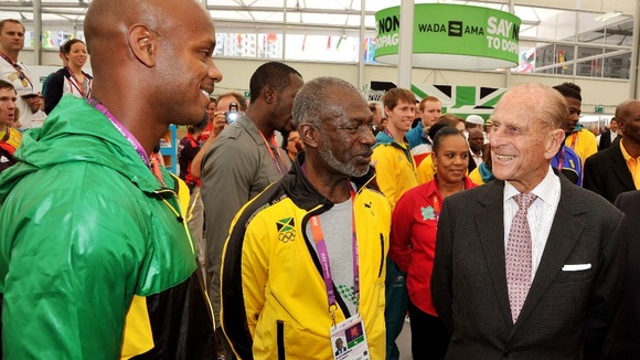 The Duke of Edinburgh talks to Jamaican sprinter Asafa Powell, during a tour of the Athletes Village.
