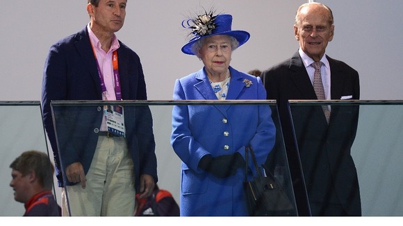 Lord Sebastian Coe, Queen Elizabeth II and the Duke of Edinburgh watch a swimming session at the Olympic Games