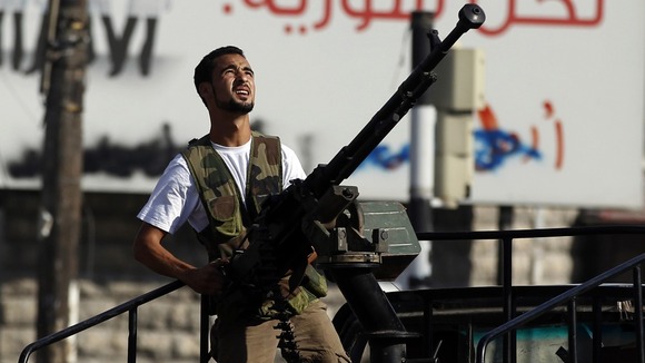 A Free Syrian Army fighter holds an anti-aircraft gun as he looks for a Syrian Air force helicopter in Aleppo