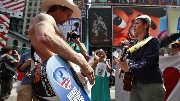 Times Square entertainer Naked Cowboy plays guitar with protester demonstrating in solidarity with Russian punk band Pussy Riot in New York