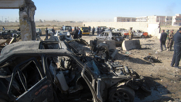 People and security forces inspect the scene of a car bomb attack in Kirkuk