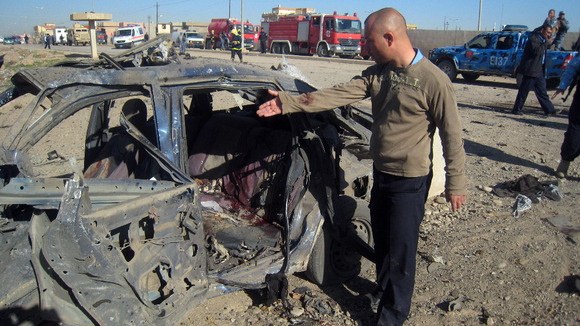 A man gestures at a destroyed vehicle at the scene of a car bomb attack in Kirkuk, Iraq