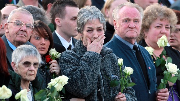 Family and friends wait to place flowers on the hearses