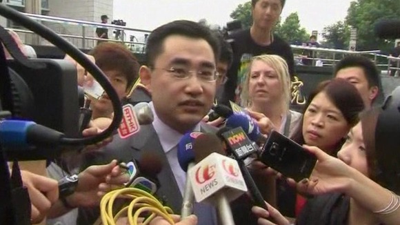 He Zhengsheng, the lawyer for the family of Neil Heywood, is surrounded by reporters as he leaves court in China