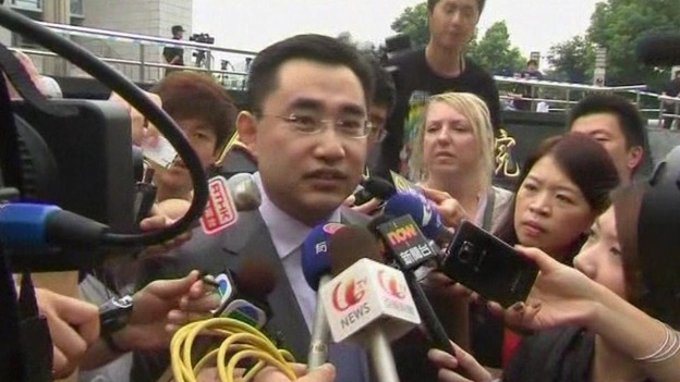 He Zhengsheng, the lawyer for the family of Neil Heywood, is surrounded by reporters as he leaves court in China