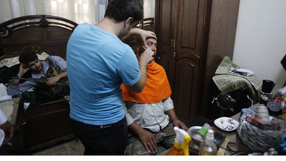 A Free Syrian Army fighter shaves his beard inside a building squatted by the fighters in the center of Aleppo city