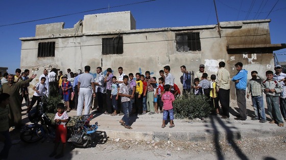 Syrians queue to buy bread at a local bakery in Aleppo city