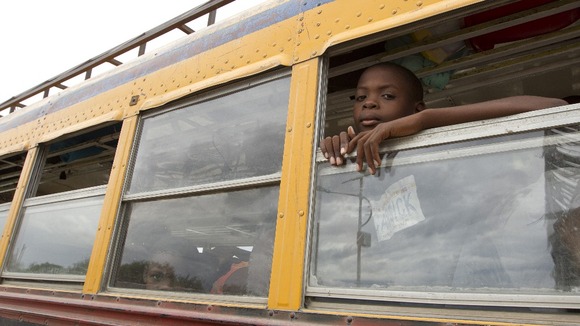 A child looks out of a bus window as residents of a camp for displaced people of the 2010 earthquake evacuate