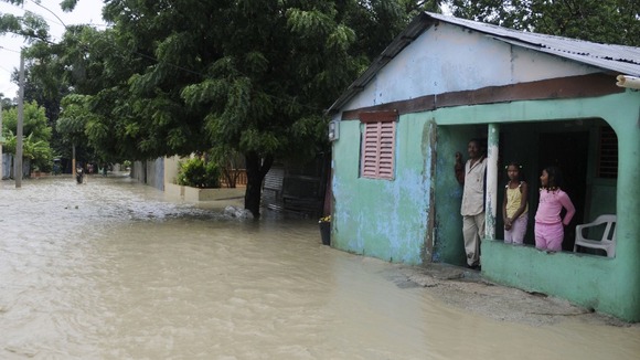 A family looks out from their porch at the floodwater from Tropical Storm Isaac in Vicente Noble