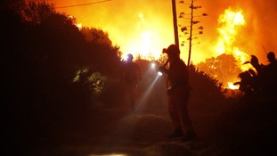 Members of the Civil Protection service look for people inside a chalet during a general evacuation at a residential area
