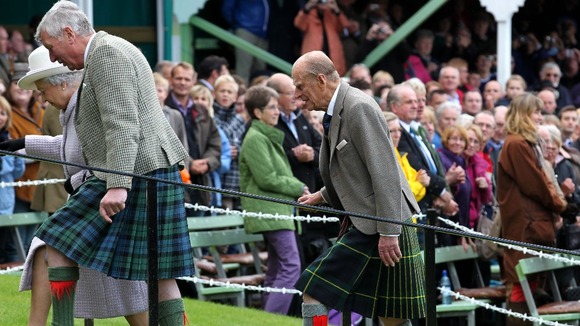 Queen Elizabeth II (left, partially obscured) accompanied by the Duke of Edinburgh (right) at the Braemar Gathering.
