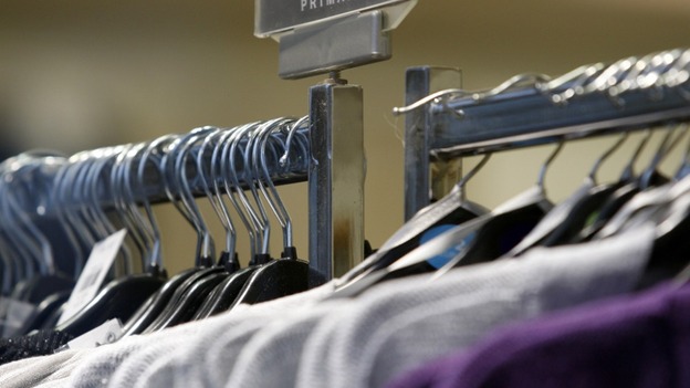 Clothes hang on a rail as sales dropped in August