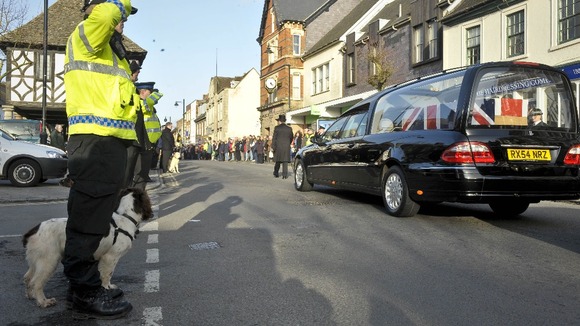 Police with dogs salute as the cortege for Lance Corporal Liam Tasker from the Royal Army Veterinary Corps passes through Wootton Bassett.