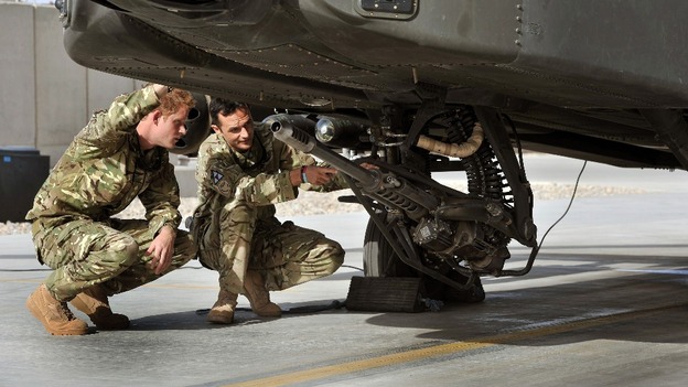 Prince Harry examines the 30mm cannon of an Apache helicopter with a member of his squadron.