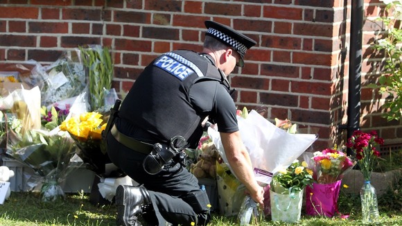 A police officer lays floral tributes from members of the public