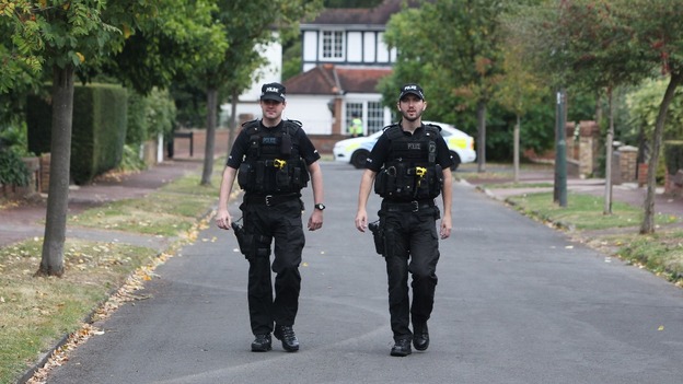 Police walk close to the home of Saad al-Hilli in Claygate, Surrey,