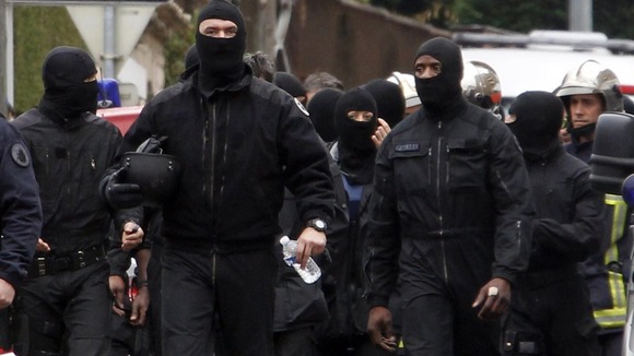 Masked French special unit policemen leave the scene after the assault to capture Mohamed Merah