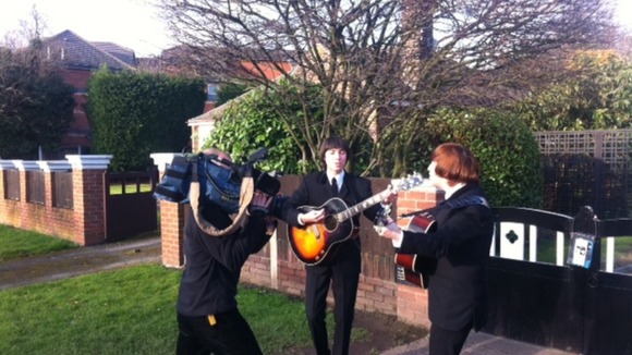 ITN Cameraman Keith Edwards films a Beatles tribute act outside the newly listed building in Liverpool
