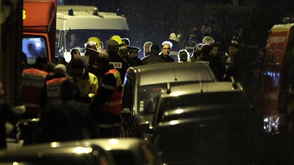 French police and emergency services gather on a street during the raid