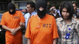 Paul Beales and Rachel Dougal are escorted by Indonesian police officers after a news conference at the police headquarters in Denpasar
