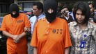 Paul Beales and Rachel Dougal are escorted by Indonesian police officers after a news conference at the police headquarters in Denpasar