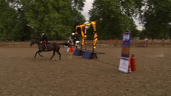 A horse from the Household Cavalry beats a motorcycle from the Royal Signals White Helmets in a race through a flaming hoop.