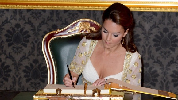 The Duchess of Cambridge signs a special book at the residence of Malaysia's king.