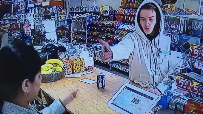 The suspect pulls a gun out on the cashier.