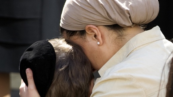A teacher comforts a child as they observe a minute of silence at a Jewish school