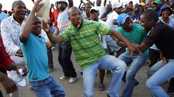 Striking miners dance and cheer after they were informed of a 22 percent wage increase offer outside Lonmin's Marikana mine