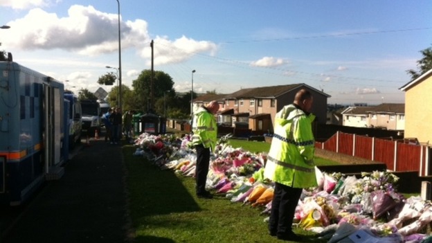 Police officers continue to lay flowers and pay their respects where two of their colleagues were killed.