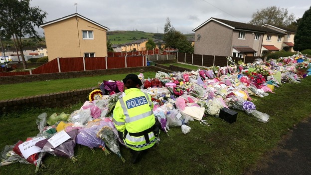 A police officer looks at flowers left at the scene of the shooting of PCs Fiona Bone, 32, and Nicola Hughes, 23, in Greater Manchester.