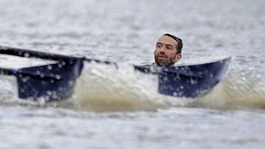 A man is seen in the water during the Oxford vs Cambridge boat race in the River Thames