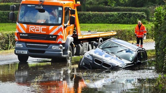 BMW in a ditch surrounded and submerged in flood water on Bristol Road in North Somerset after heavy rain affects roads across South West.