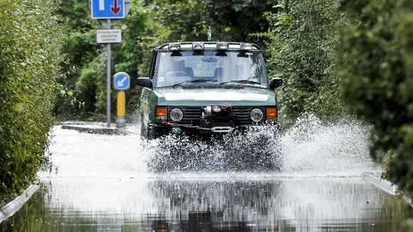 A 4x4 vehicle emerges from flood water that has closed a road on Sleep Lane, Witchurch near Bristol after heavy rain.