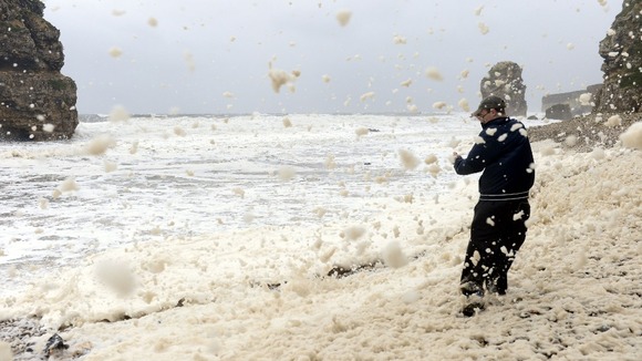 Aron Martin, 17, on Marsden beach near South Shields as heavy seas cause lots of foam along the beach.