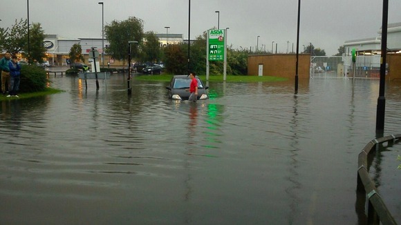 A driver wades through water at a retail park in Wigan
