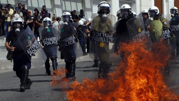 A molotov cocktail explodes beside riot police officers near Syntagma square during a 24-hour labour strike in Athens.