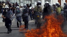 A molotov cocktail explodes beside riot police officers near Syntagma square during a 24-hour labour strike in Athens.