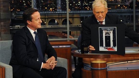 David Cameron looks on as David Letterman, holds up a picture of Larry the cat outside 10 Downing Street