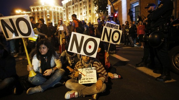 Protesters take part in a sit-in during a demonstration outside Madrid's Parliament