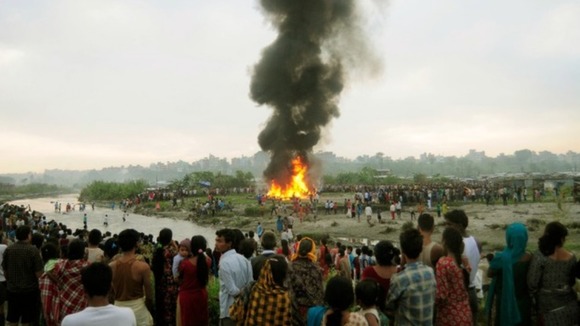 People watch the burning wreckage.