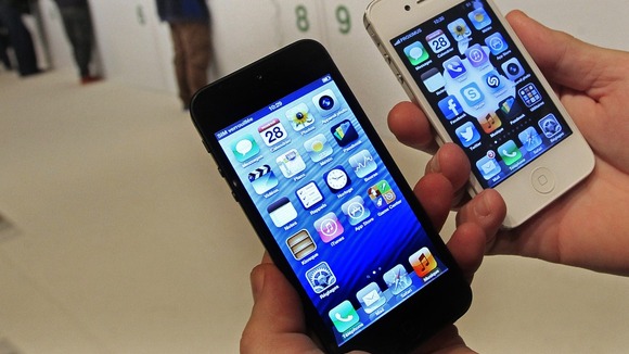 A customer holds up an Apple iPhone 5 and iPhone 4s