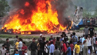 Nepalese gather around the burning wreckage at the crash site of a Sita Air airplane near Katmandu, Nepal