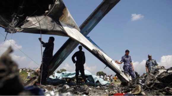 Nepalese police inspect the wreckage of a Sita Air airplane at the crash site near Katmandu, Nepal,