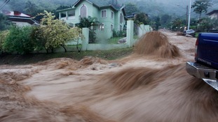 A torrent of water water rushes past a vehicle at Westvale Park, Glencoe, about 10 km (6 miles) from the capital Port-of-Spain