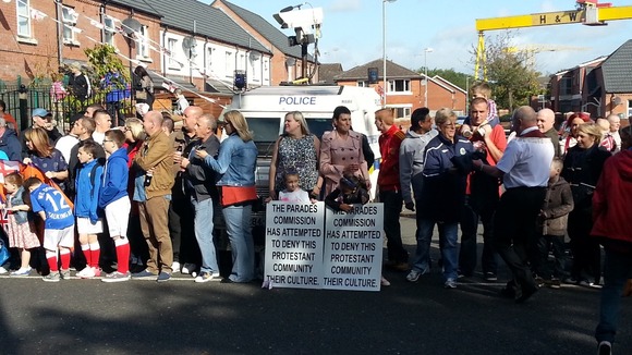 Residents of East Belfast wait for the parade to pass, in the shadow of the iconic Harland and Wolff cranes