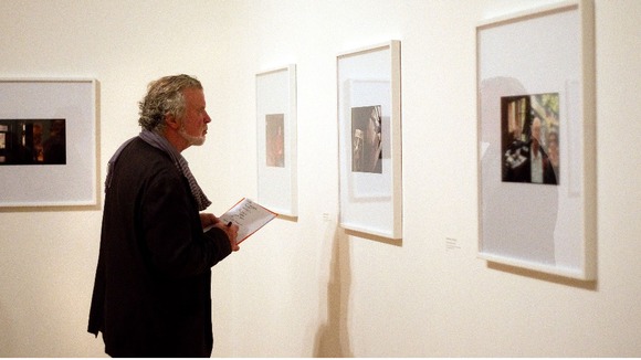 A member of the public looks at photos by Luke Fowler,